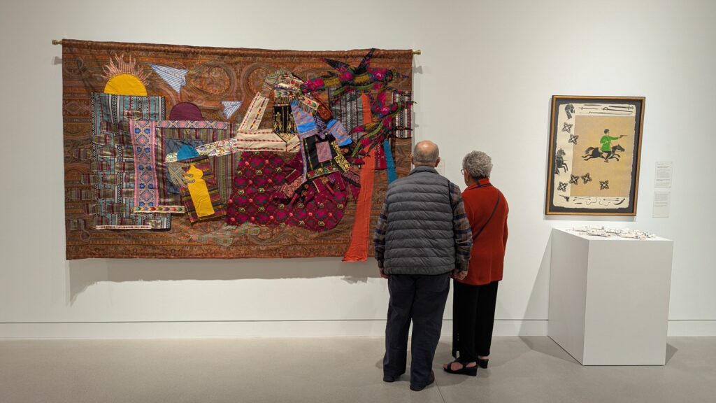 Elderly couple looking at a textile artwork in a museum.